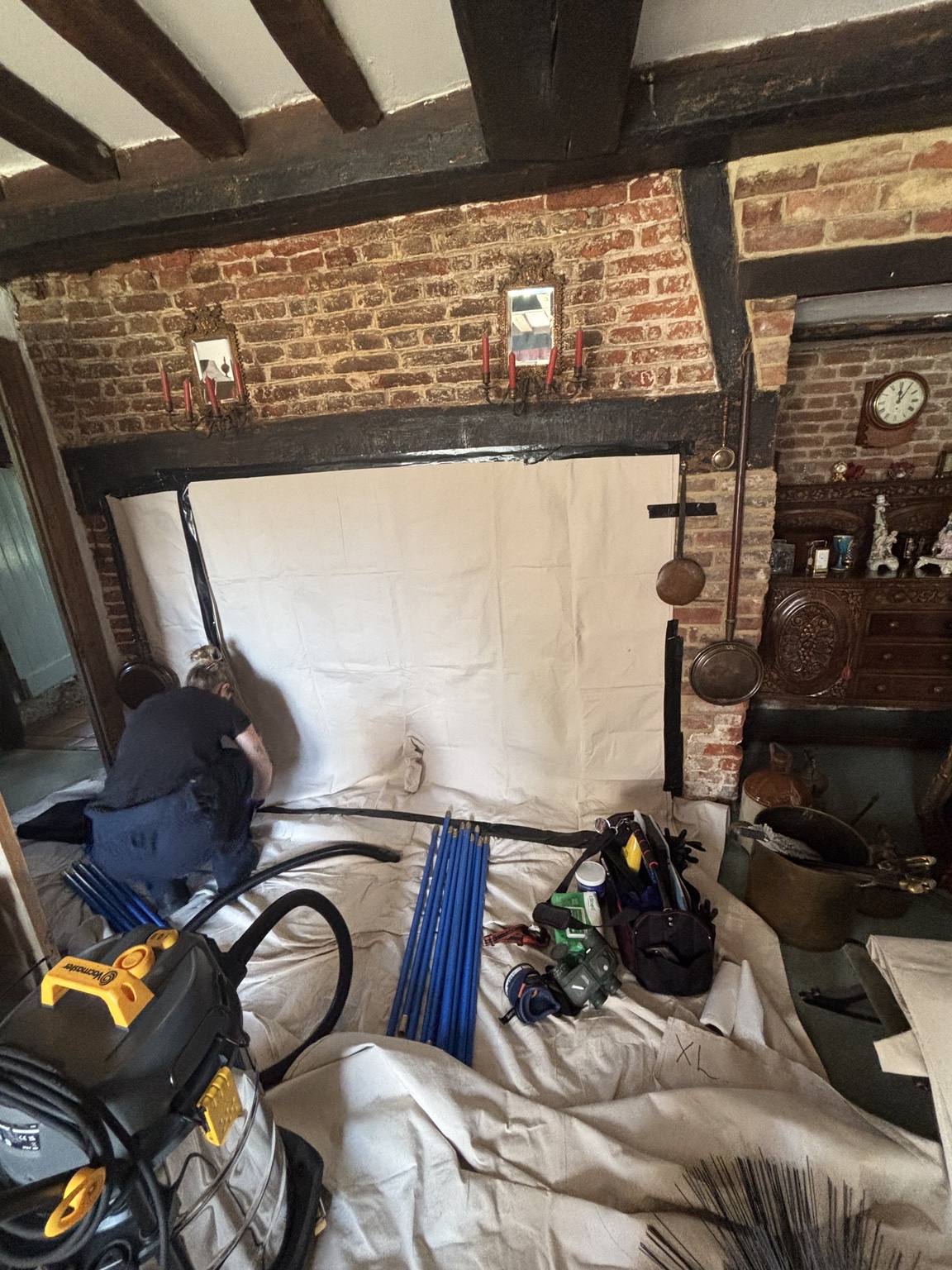 A large brick inglenook protected with sweeping sheets and chimney sweeping equipment.
